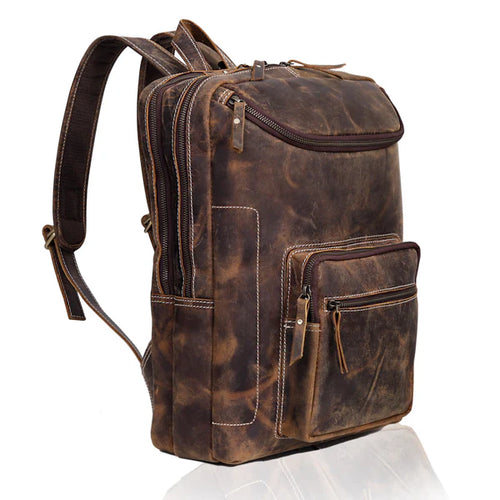A distressed brown leather backpack with multiple zippered compartments, shown from a three-quarter angle on a white background with a subtle reflection.